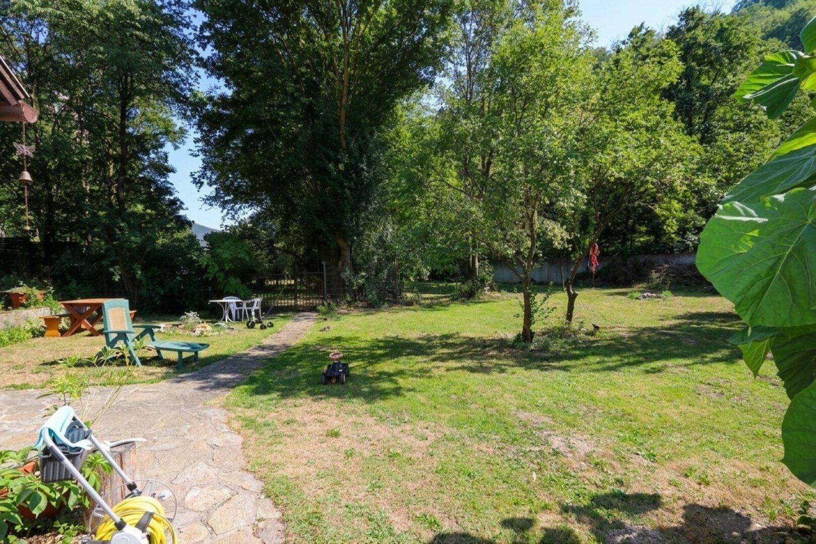 Großer Rasenbereich mit Bäumen und Gartenmöbeln, ideal für Entspannung im Freien.