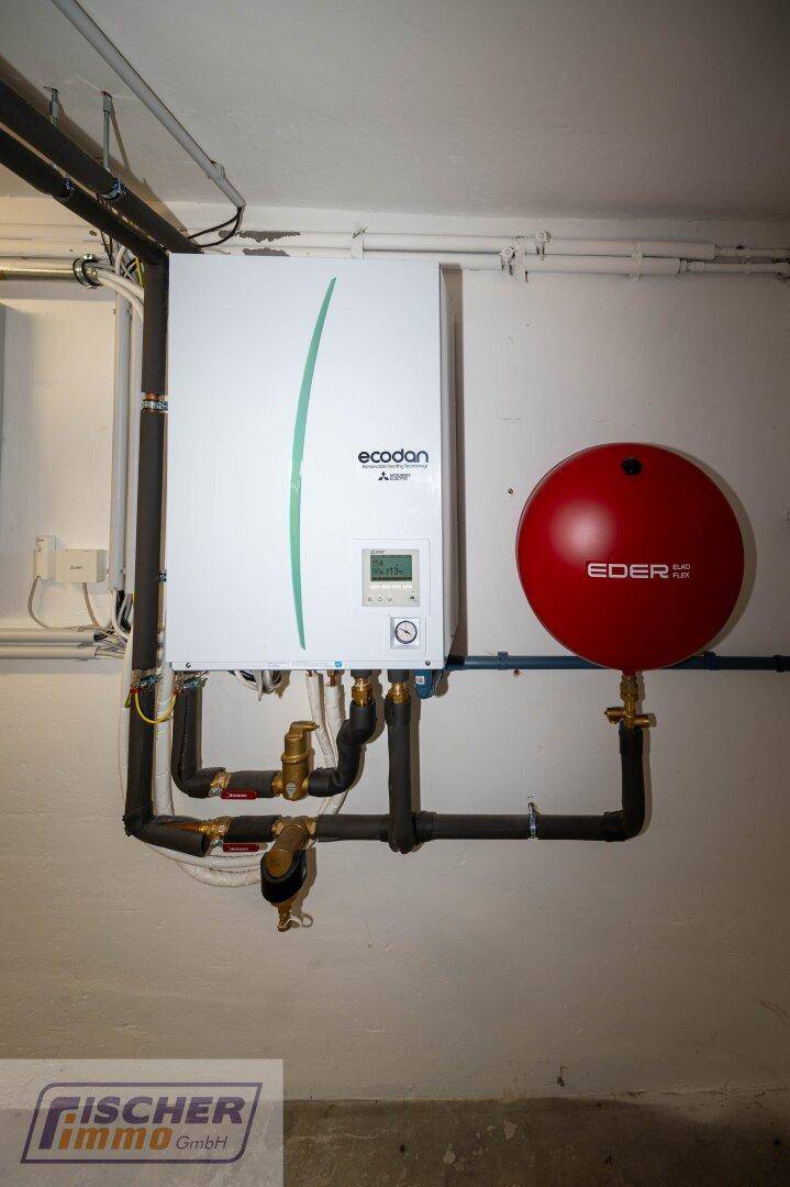 Heizungsraum mit moderner Wärmepumpe und Warmwasserspeicher.