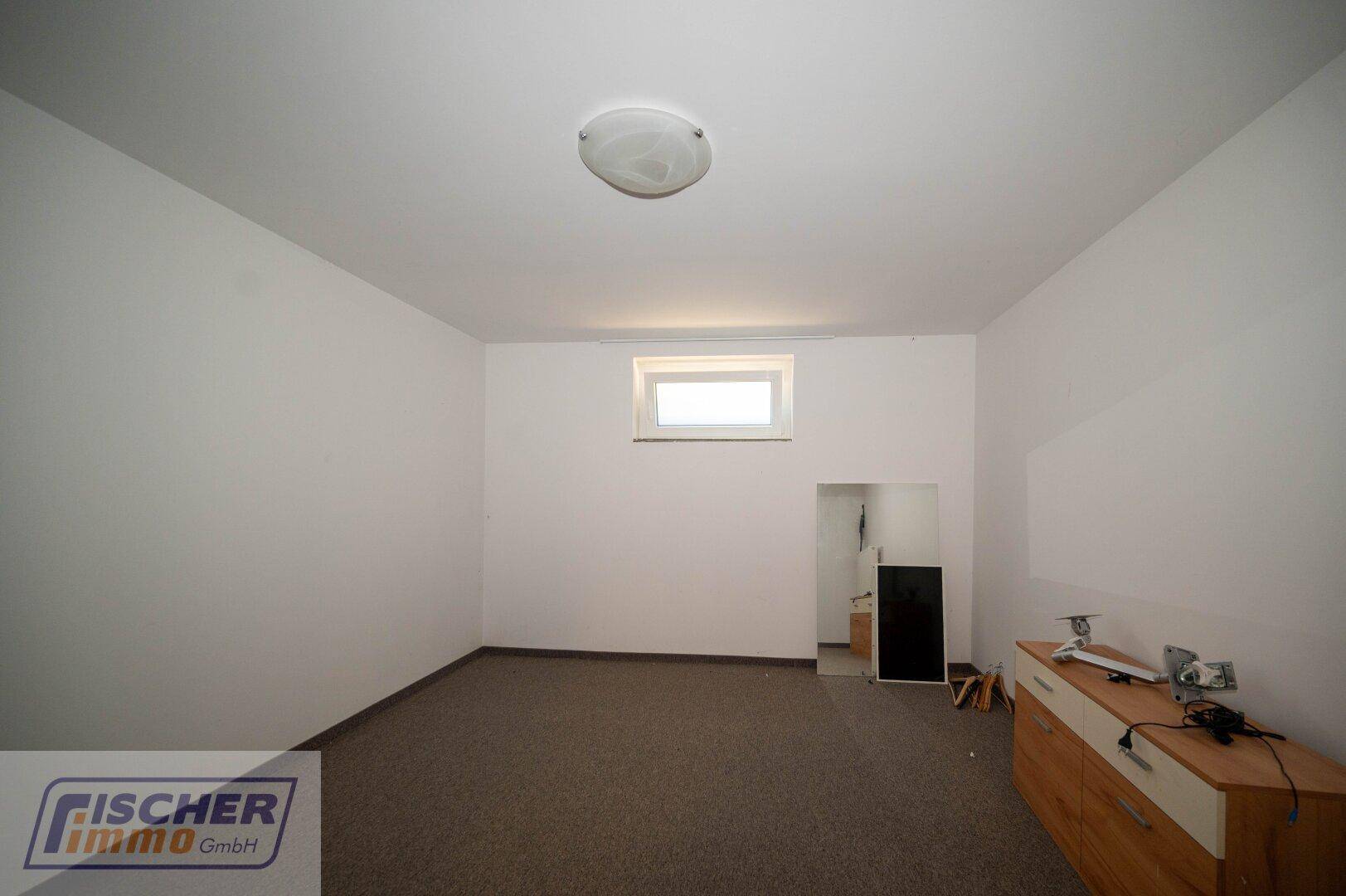Ausgebauter Kellerraum mit Teppichboden und kleinem Fenster für Tageslicht.