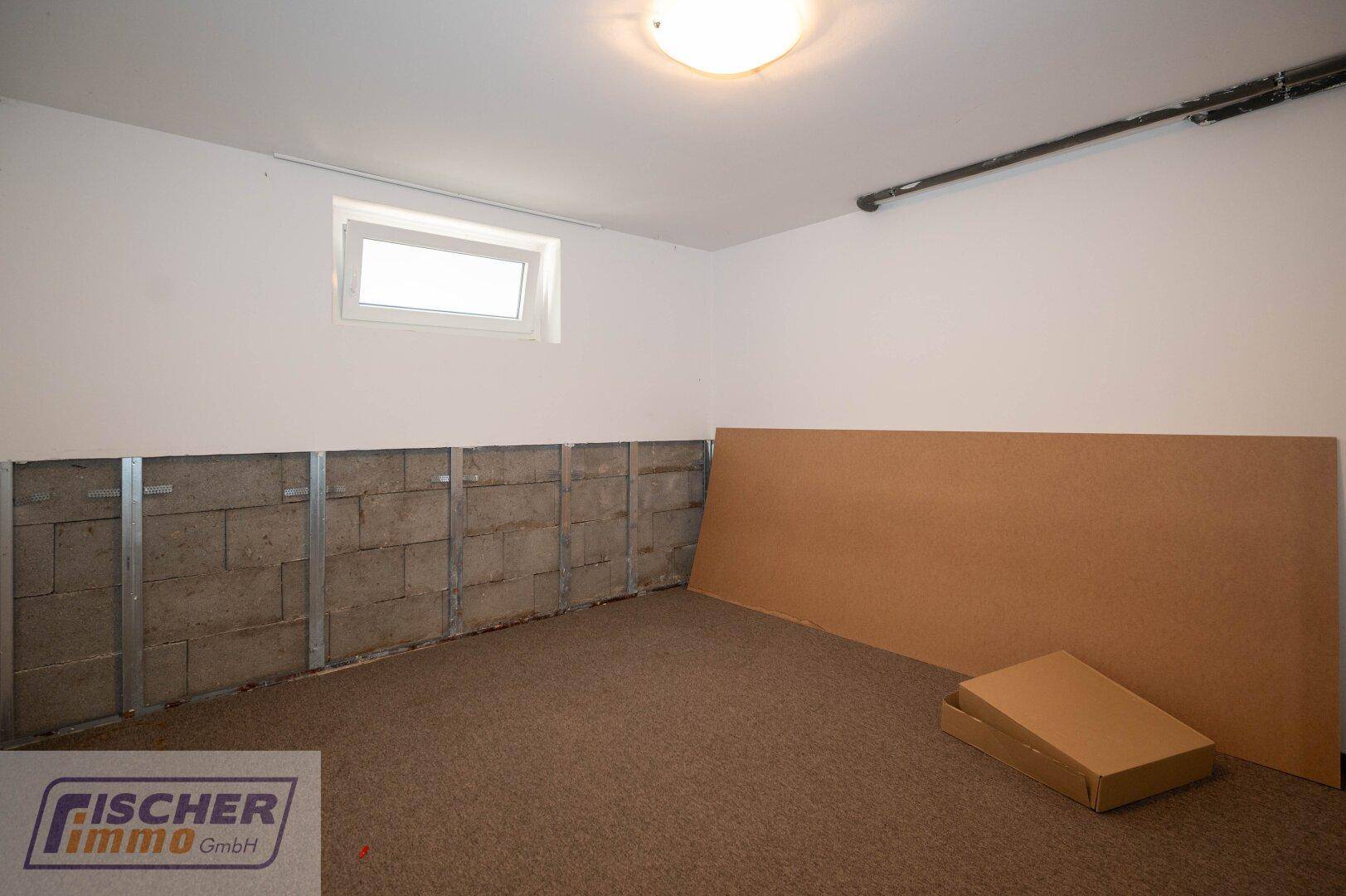 Kellerraum mit Teppichboden und vorbereiteten Wänden für den Ausbau.