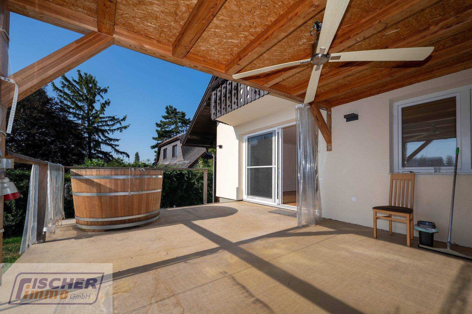 Überdachte Terrasse mit Holz-Whirlpool, Deckenventilator und Zugang zum Haus.