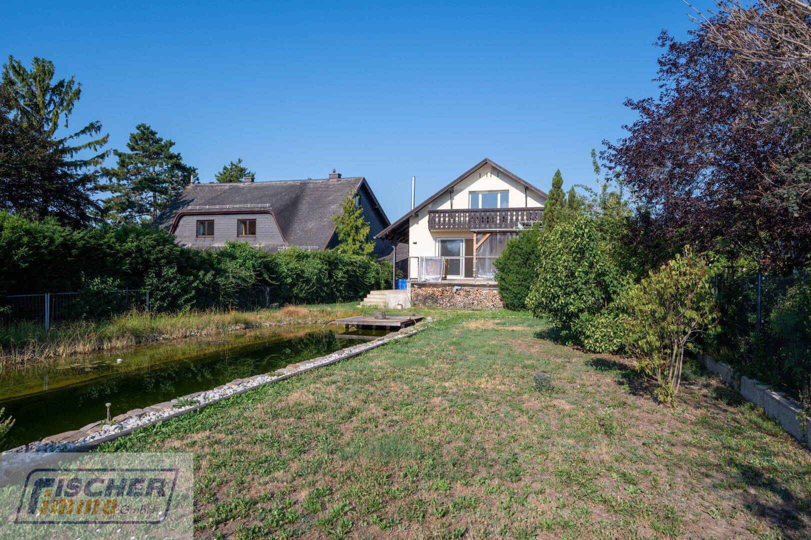 Weitläufiger Garten mit Teich und Blick auf das Einfamilienhaus.
