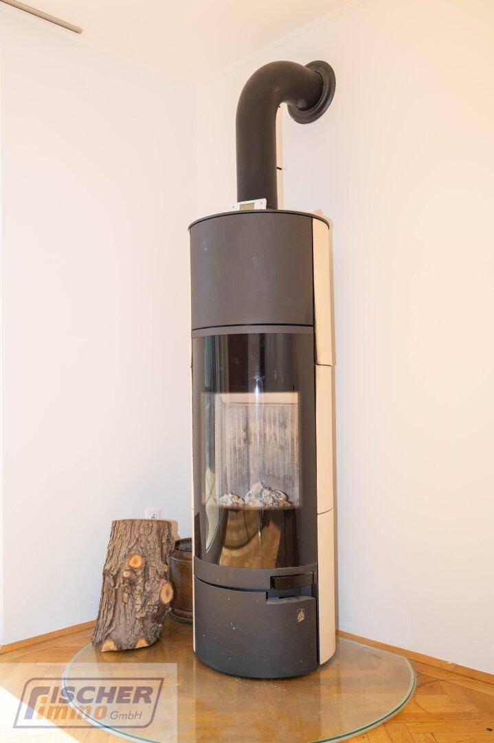 Moderner Kaminofen mit Glasfront und Holzscheiten auf einem Glasboden.