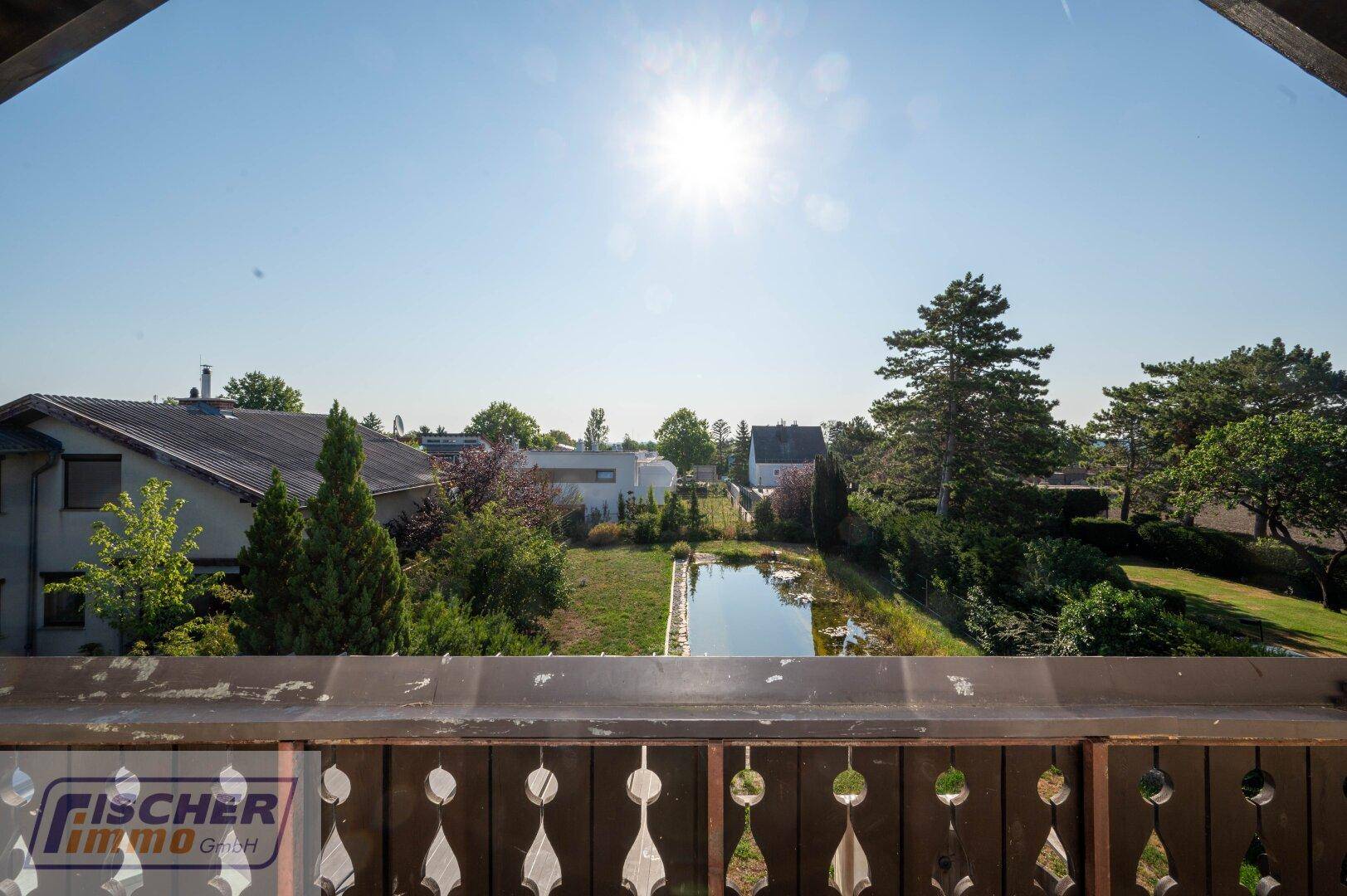 Panoramablick vom Balkon auf den Garten mit Teich und die umliegende Landschaft.