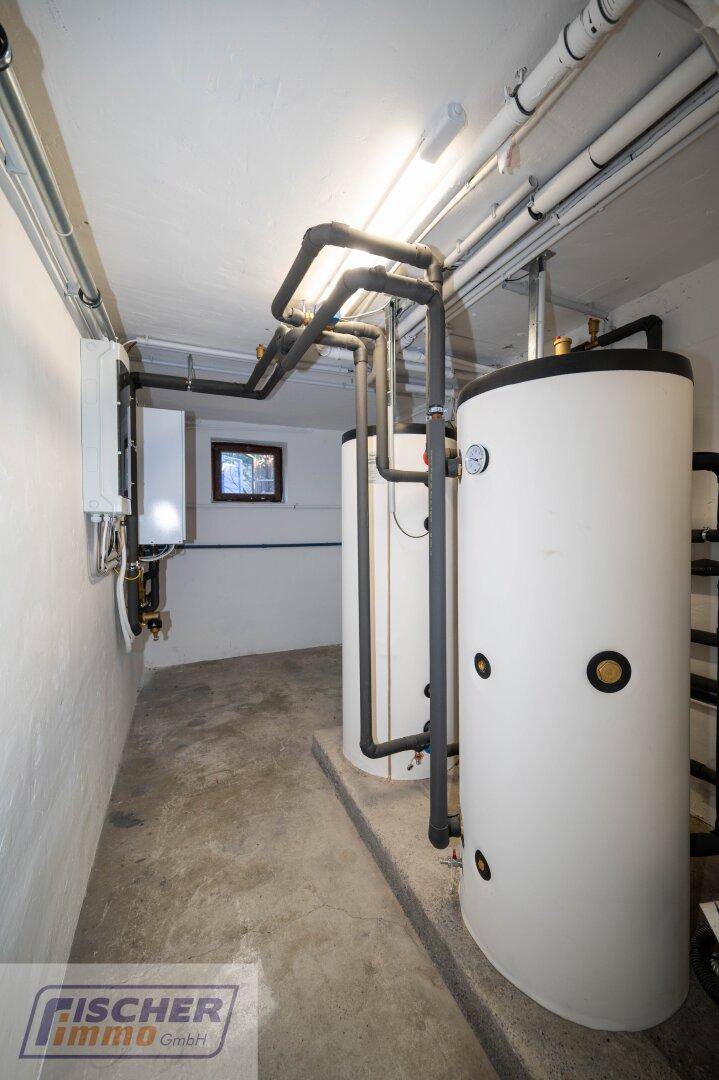 Heizungsraum mit zwei Warmwasserspeichern und komplexen Rohrleitungen.