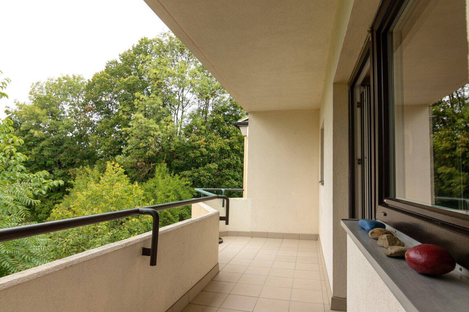 Langer Balkon mit Fliesenboden und weitem Blick auf die umliegende grüne Landschaft.