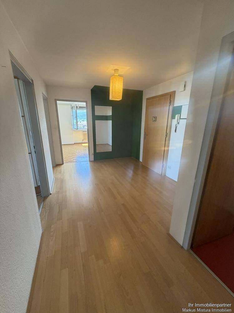 Heller Flur mit Parkettboden und einem farbigen Akzent an der Wand.