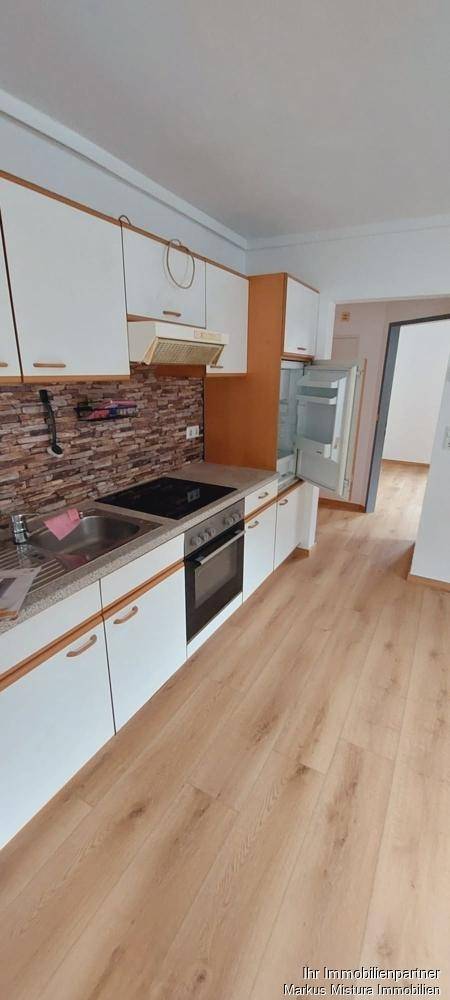 Funktionale Küche mit weißen Schränken, Induktionskochfeld und Backofen, bereit zur Nutzung.