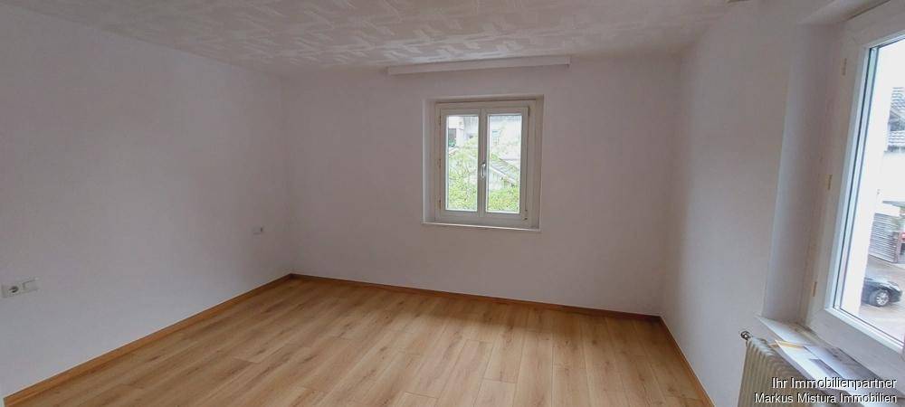 Geräumiges Zimmer mit hellem Laminatboden und zwei Fenstern, bietet vielseitige Gestaltungsmöglichkeiten.