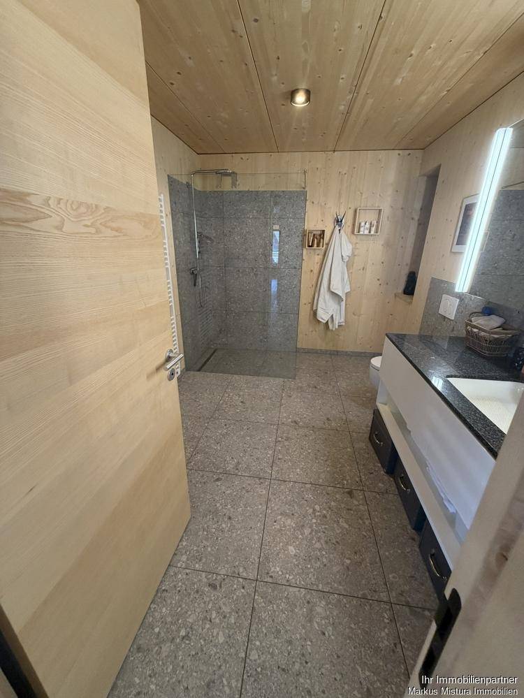 Modernes Badezimmer mit begehbarer Dusche, Holzverkleidung und Fliesenboden.