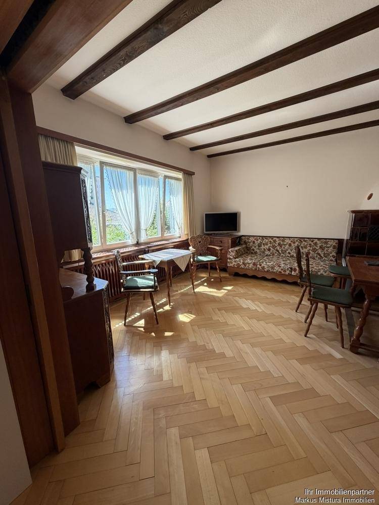 Essbereich mit Fischgrätparkett, Holzbalken an der Decke und großen Fenstern mit viel Tageslicht.