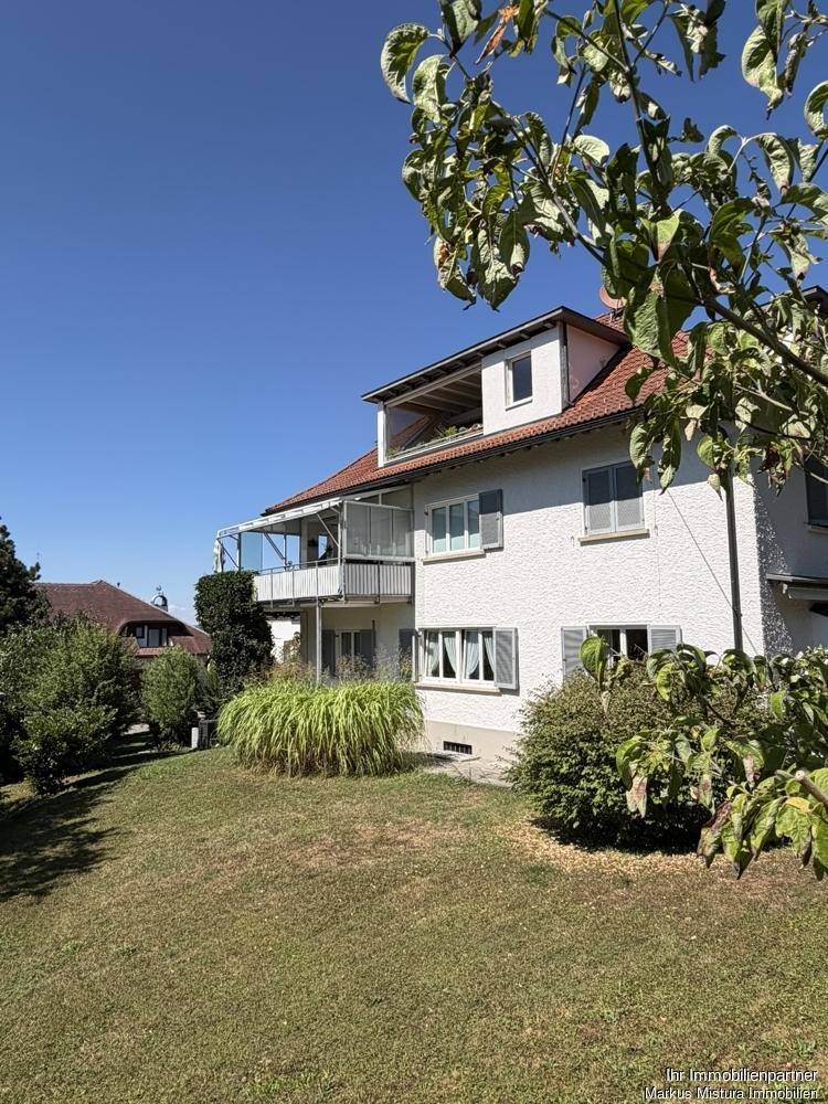 Ansicht des Hauses vom Garten aus, mit gepflegtem Rasen, Bäumen und der Gebäudefassade.