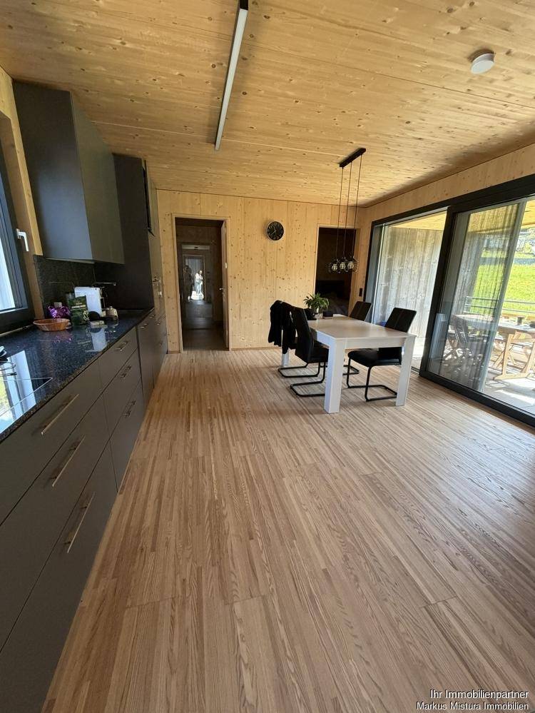 Moderne offene Küche mit dunklen Schränken, Essbereich und Zugang zur Terrasse.