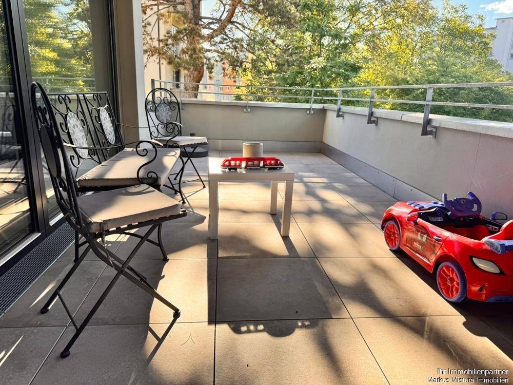 Geräumiger Balkon mit Fliesenboden, Gartenmöbeln und Blick ins Grüne, ideal für entspannte Stunden im Freien.