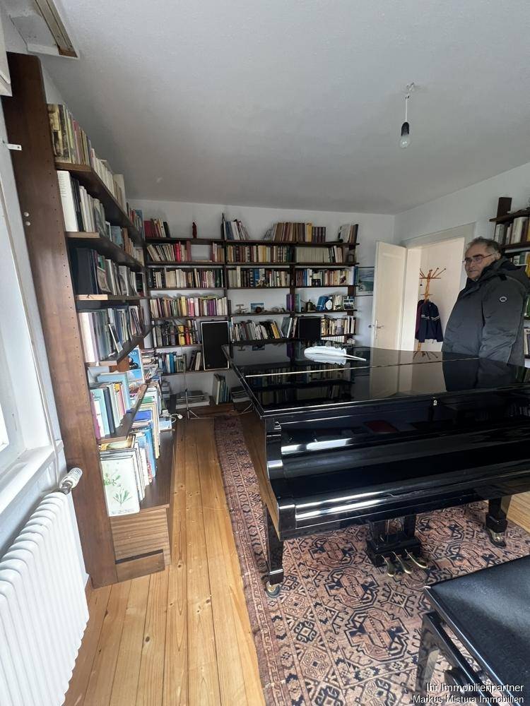 Geräumiges Arbeitszimmer mit umfangreichen Bücherregalen und einem eleganten Flügel.