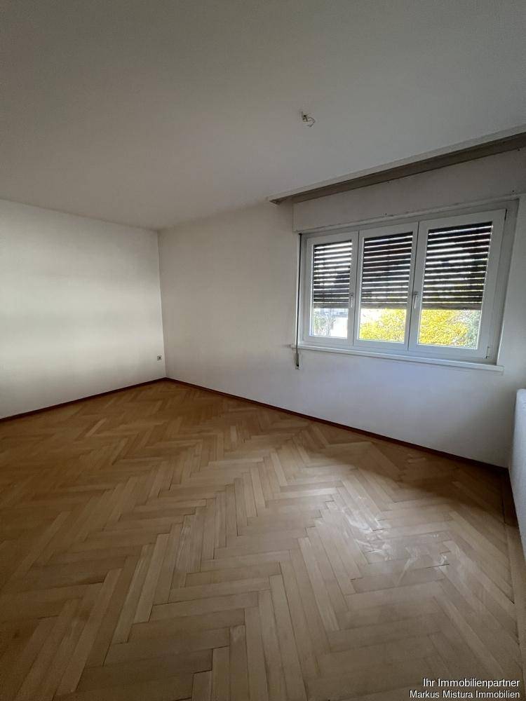 Geräumiges Zimmer mit Fischgrätparkett und viel Tageslicht, bereit zur individuellen Gestaltung.