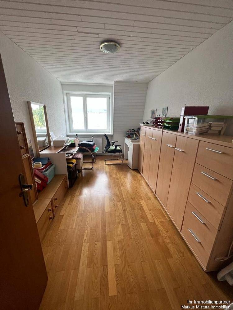 Arbeitszimmer mit Holzfußboden, weißer Holzdecke und praktischen Schranksystemen.