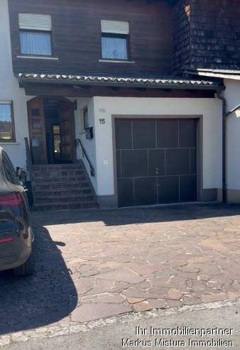 Eingangsbereich eines Hauses mit Garage und gepflasterter Auffahrt.