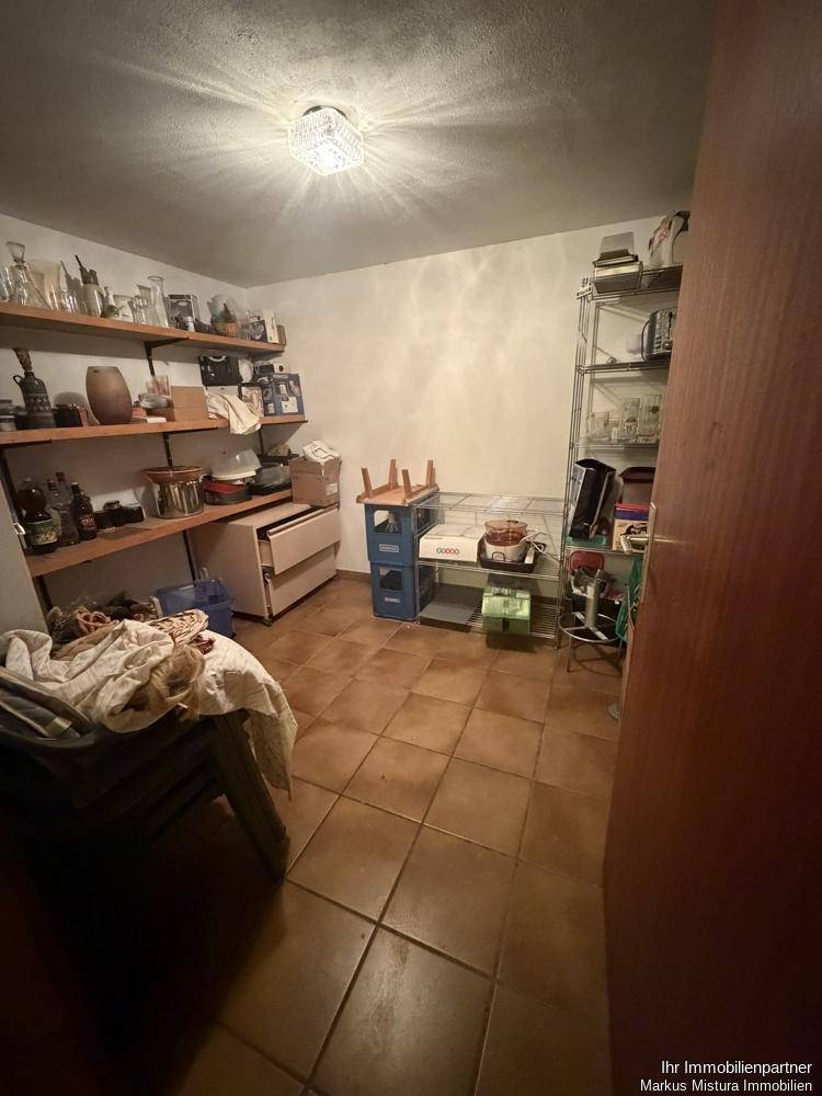 Abstellraum mit Regalen, Fliesenboden und verschiedenen Haushaltsartikeln.