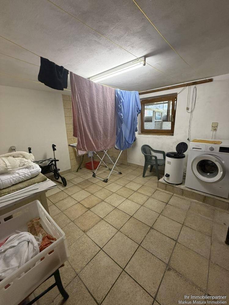 Waschküche im Keller mit Waschmaschine, Trockner und Wäscheleine.