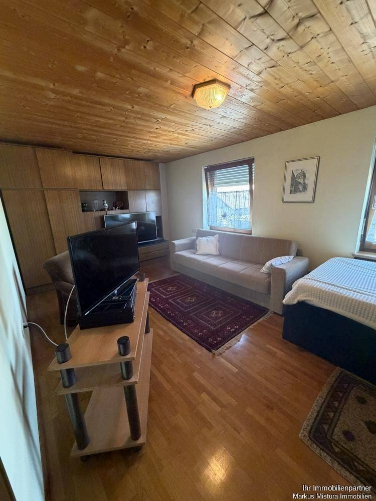 Gemütliches Wohnzimmer mit Holzdecke, Parkettboden und bequemer Couch.