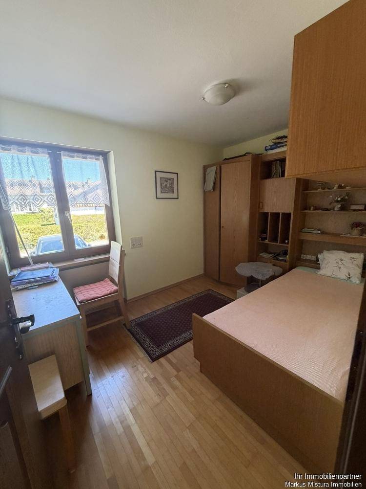 Kinderzimmer oder Gästezimmer mit Holzboden, Schreibtisch und Fenster.