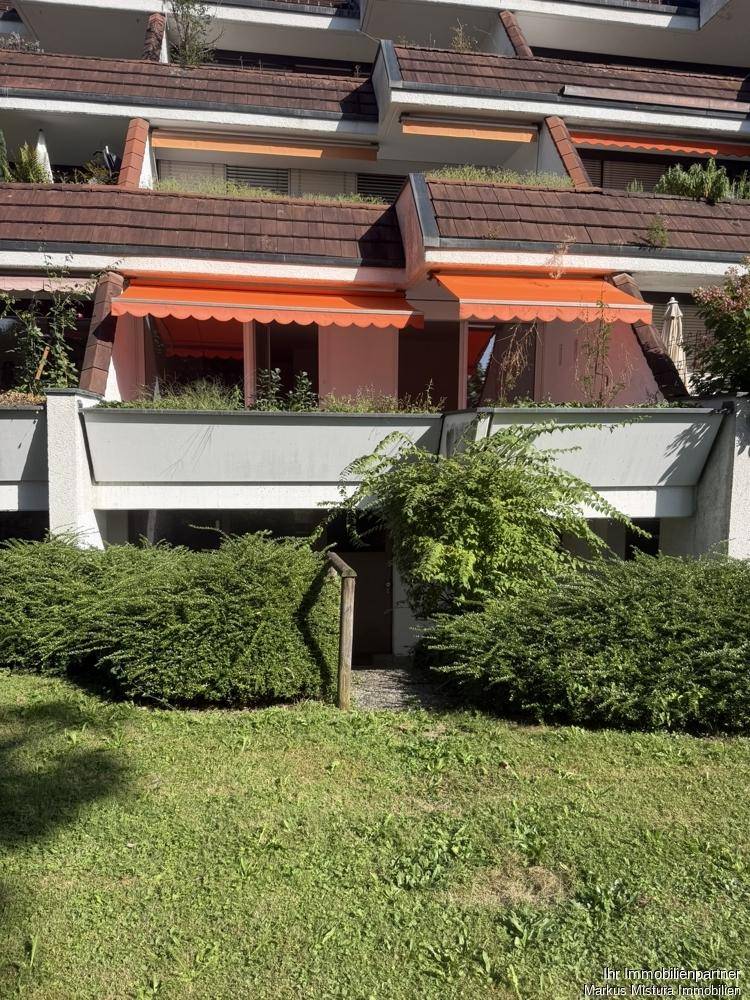 Grüne Gartenanlage vor dem Gebäude mit gepflegten Hecken und Rasenflächen.