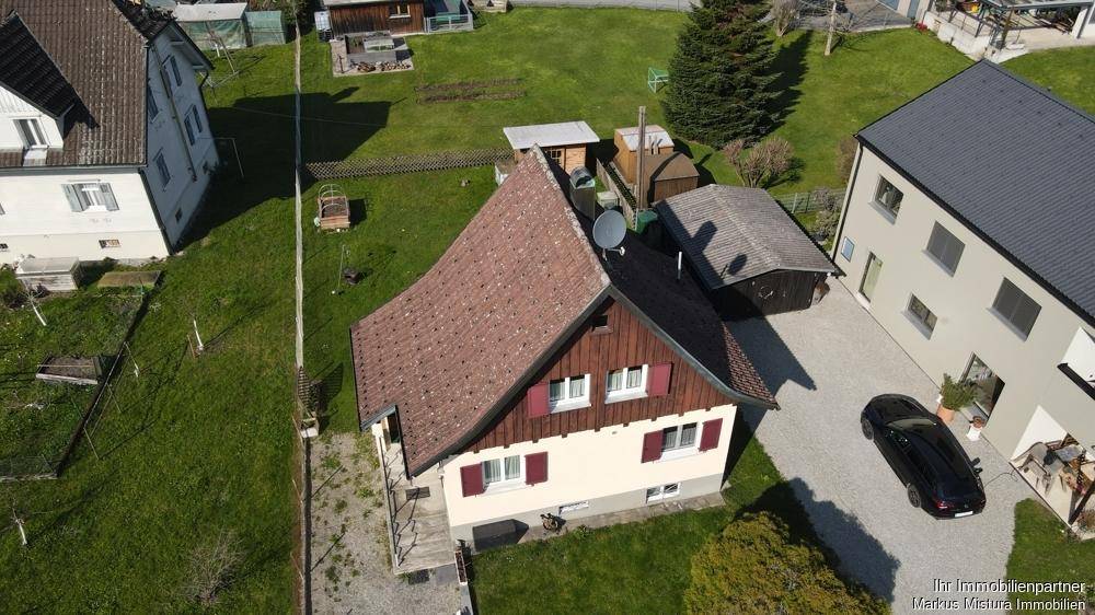Draufsicht auf ein Einfamilienhaus mit angrenzendem Schuppen und gepflegtem Gartenbereich.