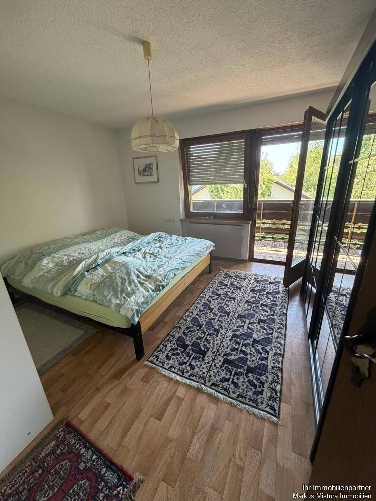 Helles Schlafzimmer mit Holzboden und Zugang zu einem Balkon.