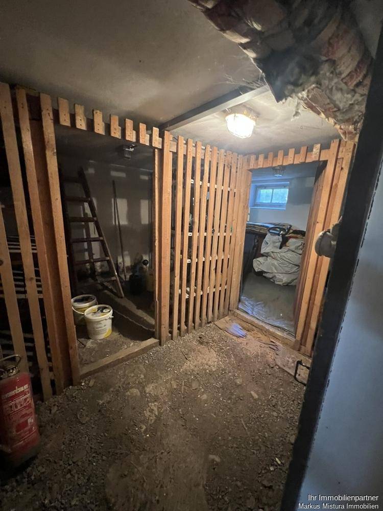 Kellerbereich mit mehreren Holzlattenverschlägen und unfertigem Boden.