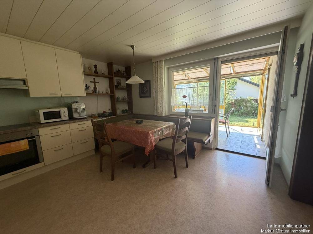 Küche mit Einbauschränken, Essbereich und direktem Zugang zur Terrasse.