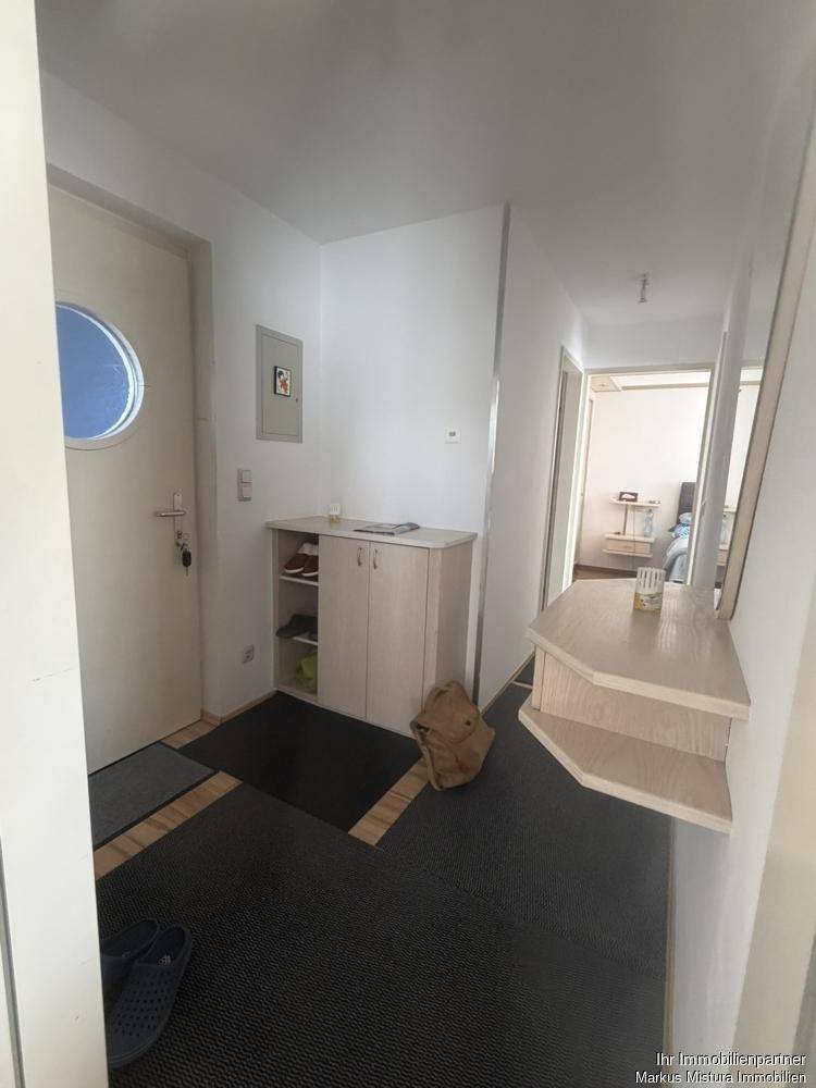 Heller Eingangsbereich mit Schuhschrank, Spiegel und Zugang zu weiteren Räumen.