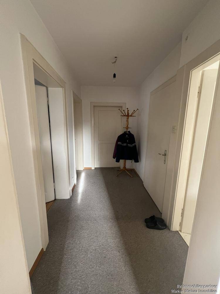 Heller Flur mit Teppichboden, Garderobe und mehreren Türen zu den Zimmern.