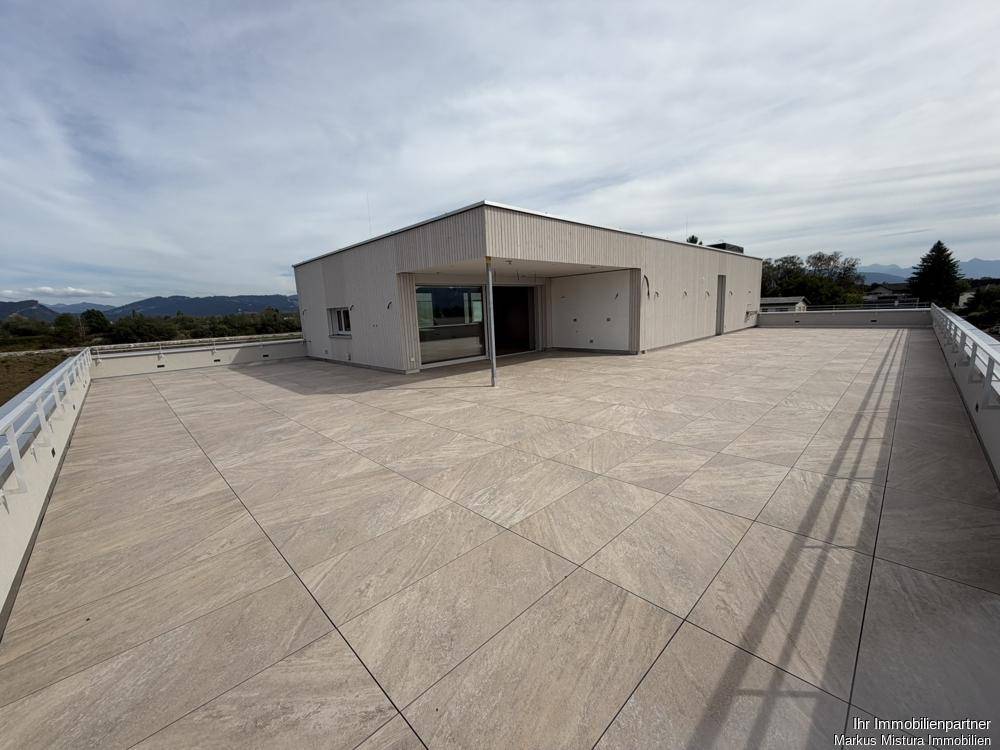 Weitläufige, geflieste Dachterrasse mit moderner Gestaltung und Blick in die Ferne.