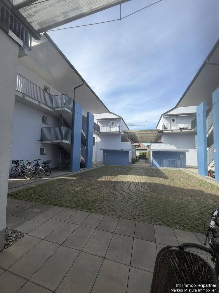 Innenhof einer Wohnanlage mit begrünten Parkflächen und Zugängen zu den einzelnen Wohneinheiten.