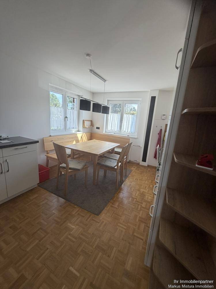 Gemütliche Wohnküche mit Essbereich, Holztisch und Parkettboden, ideal für Familienmahlzeiten.