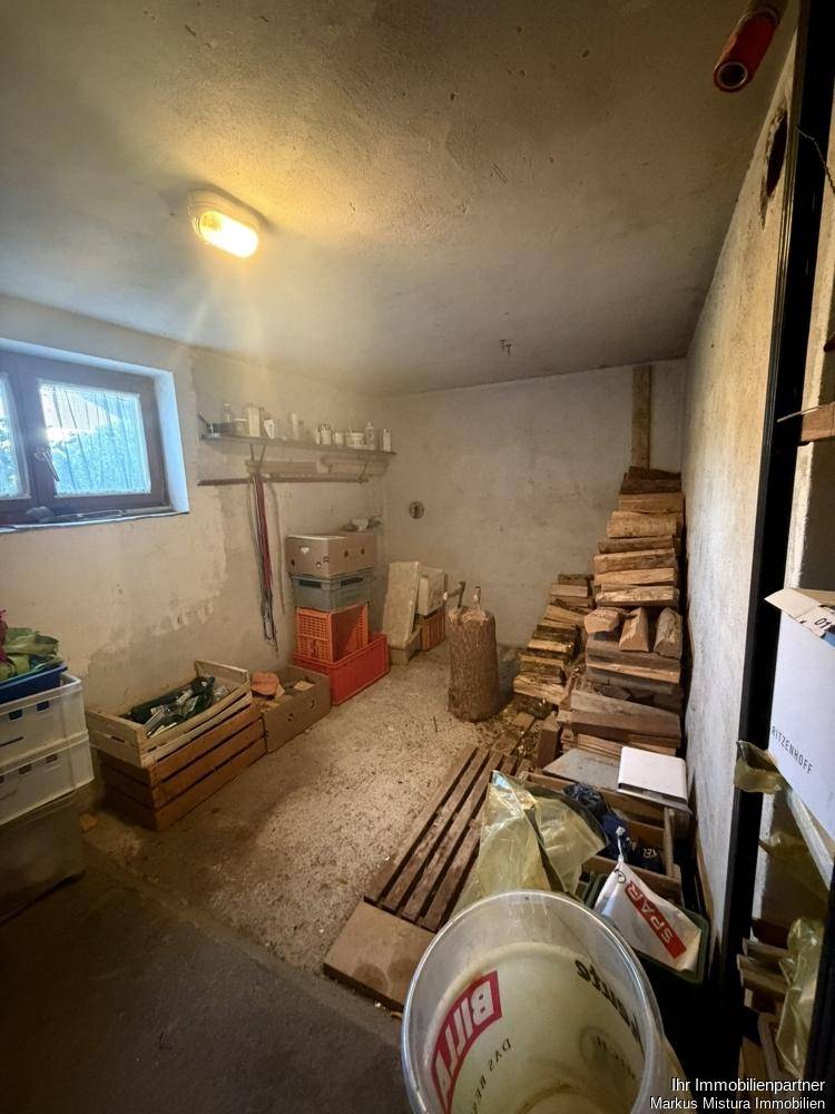 Kellerraum zur Lagerung von Holz und anderen Gegenständen mit kleinem Fenster.