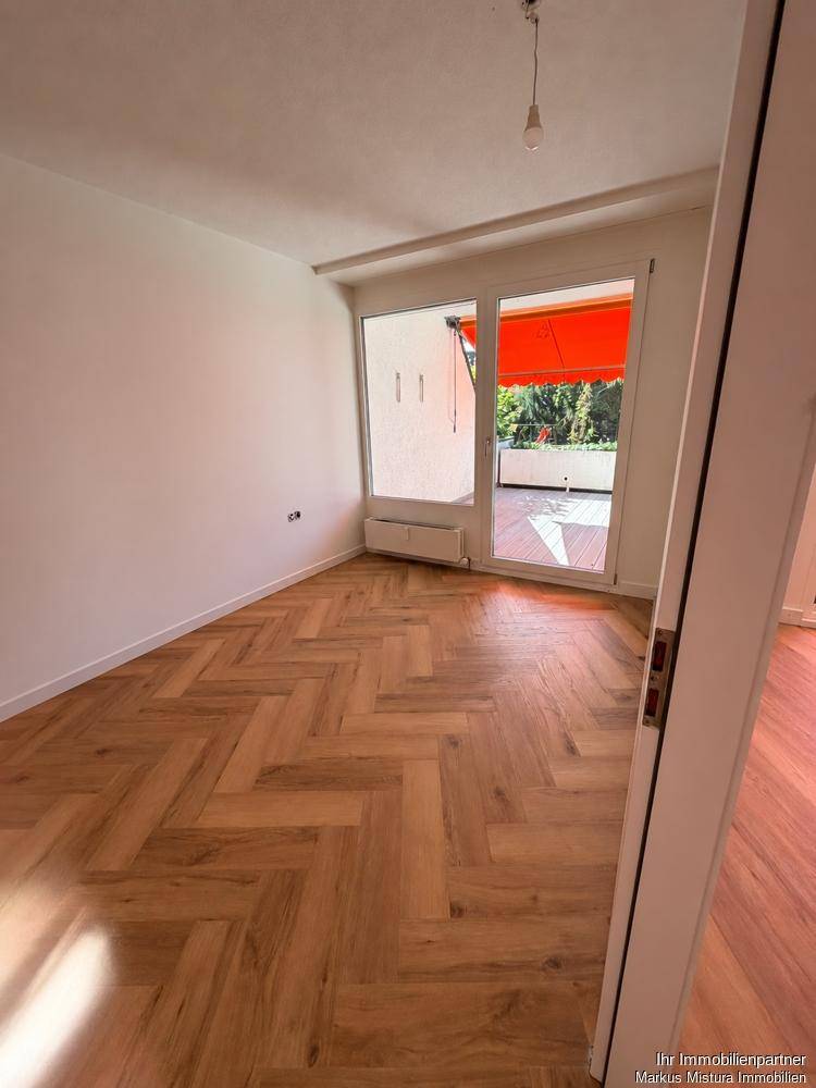 Heller Wohnraum mit neuem Fischgrätparkett und Zugang zur sonnigen Terrasse.