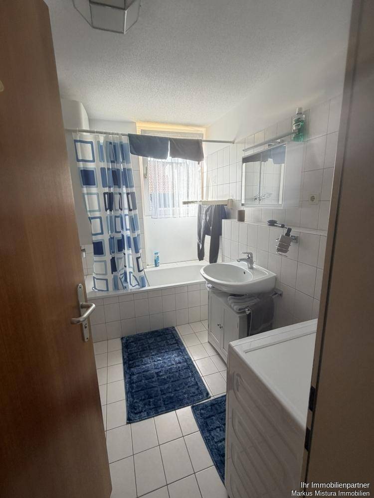 Helles Badezimmer mit Badewanne, Waschbecken und weißen Fliesen.