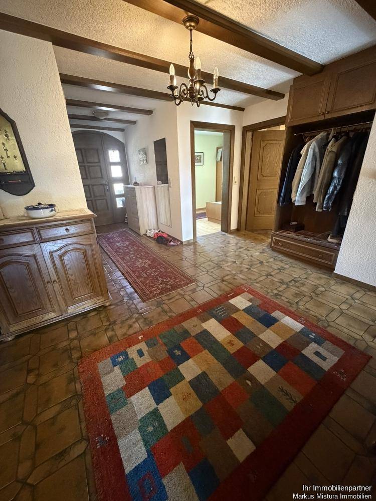 Geräumiger Eingangsbereich mit Fliesenboden, Holzbalken und Garderobe.