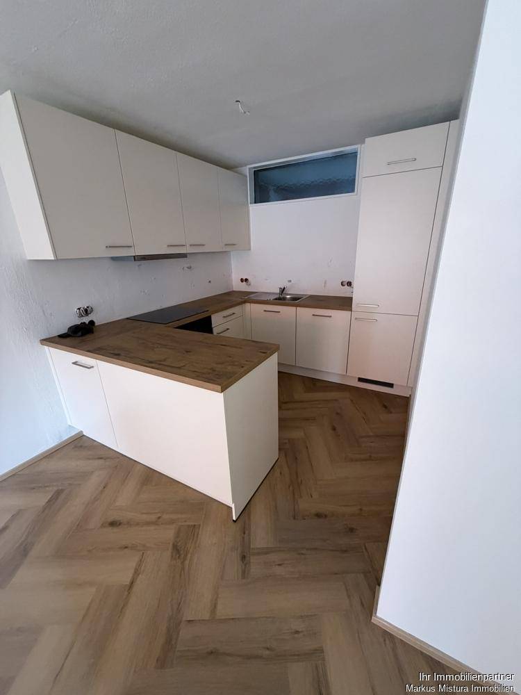 Neue, moderne Küche mit weißen Schränken, Holz-Arbeitsplatten und viel Stauraum.