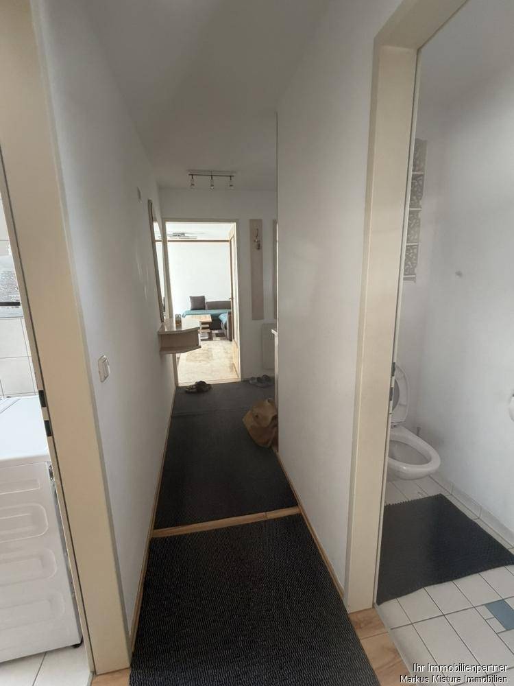 Schmaler Flur mit Blick auf das Badezimmer und den Wohnbereich.
