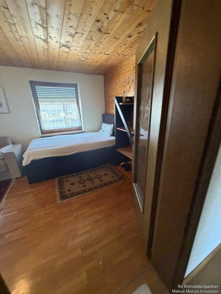 Schlafzimmer mit Holzboden, Holzdecke und einem Einzelbett.