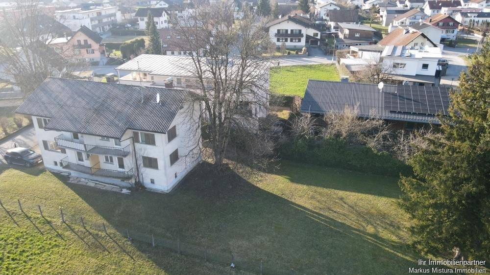 Übersicht des Grundstücks mit Wohnhaus, Photovoltaikanlage auf Nachbargebäude und viel Grün.