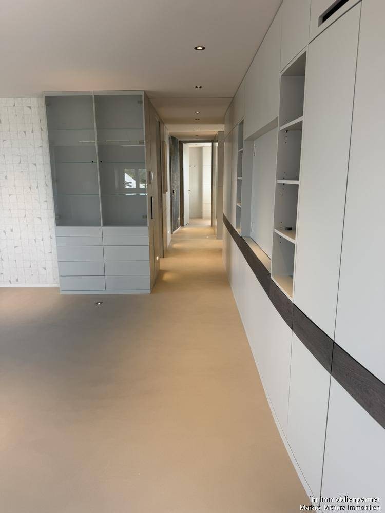 Langer Flur mit eleganten Einbauschränken und integrierten Vitrinen für Stauraum.