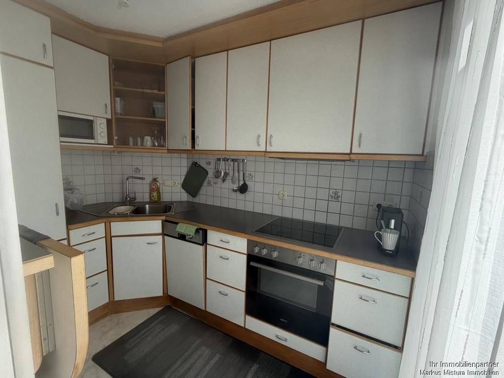 Funktionale Küche mit weißen Schränken, dunkler Arbeitsplatte und integrierten Geräten.