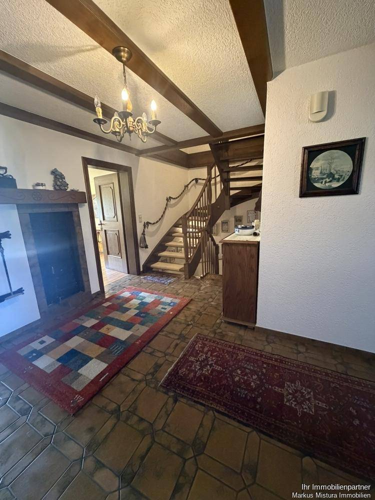 Eingangsbereich mit Fliesenboden, Holztreppe und traditionellem Kronleuchter.