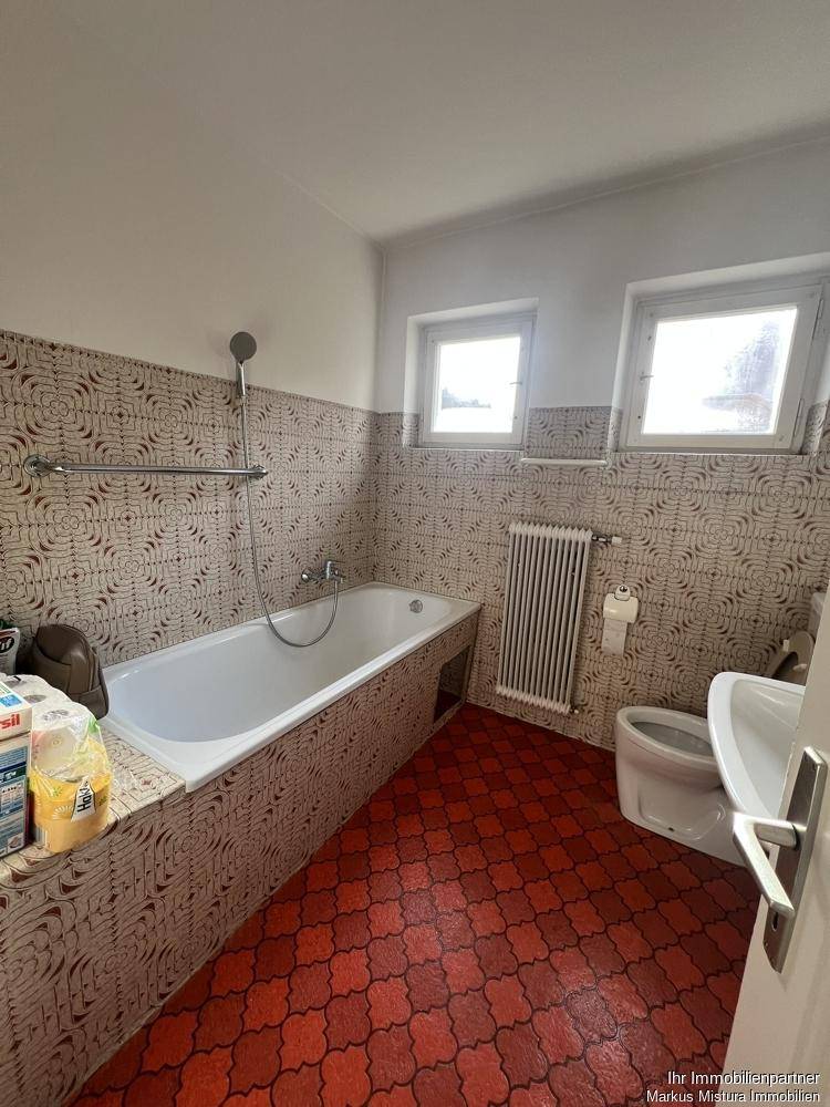Badezimmer mit Badewanne, WC und auffälligen roten Fliesen im Retro-Stil.