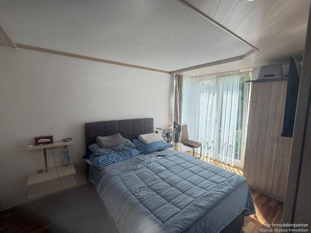 Gemütliches Schlafzimmer mit Doppelbett, Kleiderschrank und Zugang zum Balkon oder Garten.
