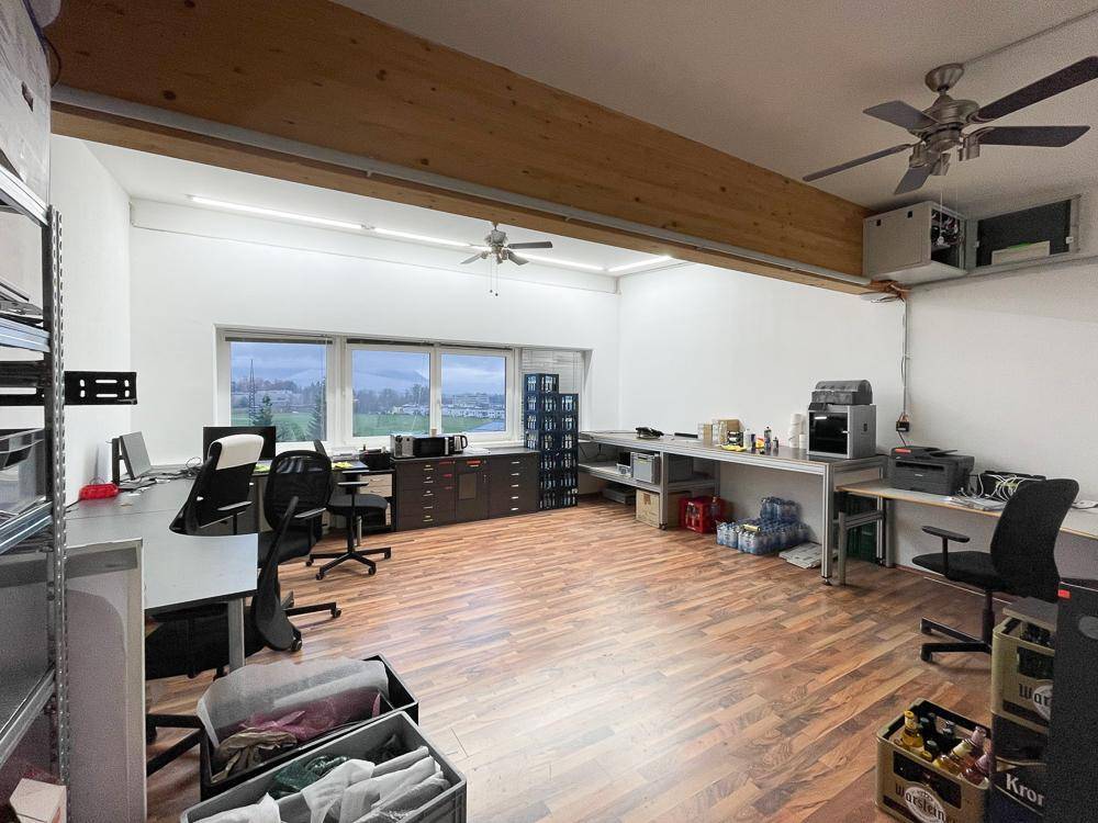 Bürofläche mit Holzfußboden, Deckenventilatoren und Blick ins Grüne durch die Fenster.